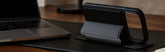 black phonecase on a desk with a computer and lamp in the background