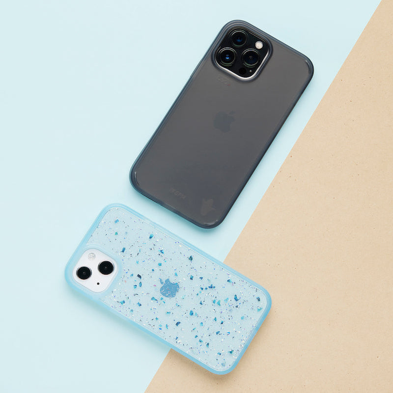 Two phone cases, one black and one speckled blue, on a light blue and beige background.